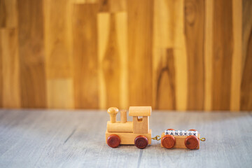 
Miniature figure wood train toy carry block Bangkok  text over wooden background
