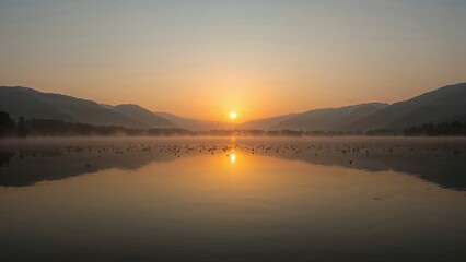 Fototapeta premium A tranquil and dreamy scene of a misty lake at daybreak, with golden hues reflected on the still surface, encircled by dark hill silhouettes