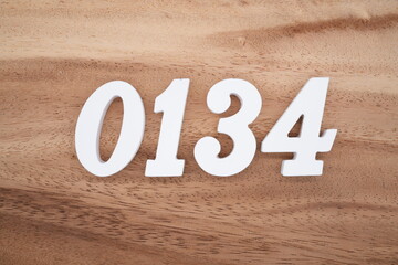 The numbers are made of white painted wood placed on a brown wooden floor.
