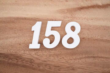 The numbers are made of white painted wood placed on a brown wooden floor.