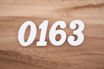 The numbers are made of white painted wood placed on a brown wooden floor.