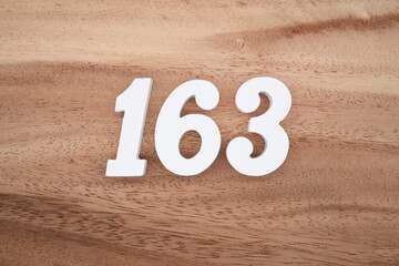 The numbers are made of white painted wood placed on a brown wooden floor.