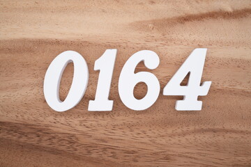 The numbers are made of white painted wood placed on a brown wooden floor.
