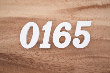 The numbers are made of white painted wood placed on a brown wooden floor.