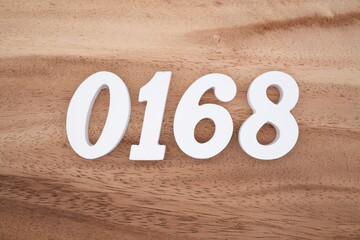 The numbers are made of white painted wood placed on a brown wooden floor.