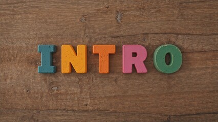 Fototapeta premium Alphabet letter blocks forming the word 'intro' on a wooden surface