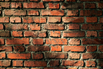 Sunlight illuminating red brick wall creating shadows.