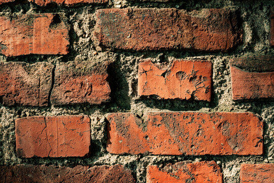 Close-up of weathered red brick wall showing signs of age and decay.