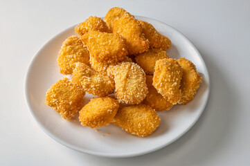 Golden chicken nuggets isolated on a white background, showcasing crispy fried chicken. Natural light highlights this popular junk food, perfect for fast food and street food lovers.

