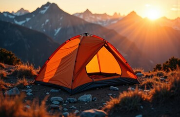Bright orange camping tent set up in a mountainous landscape during sunset