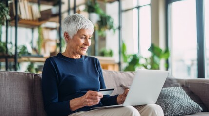 The woman shopping online happily with a laptop and credit card at home.