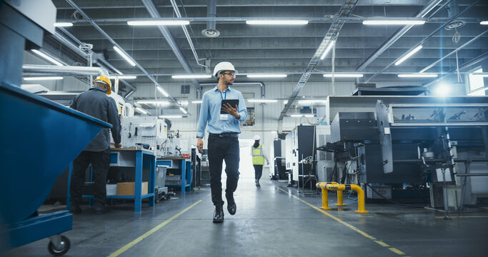 Chief Technical Officer Working at Metal Components Production Factory. Young Middle Eastern Specialist Walking in the Facility, Using Tablet Computer to Monitor the Manufacturing Process