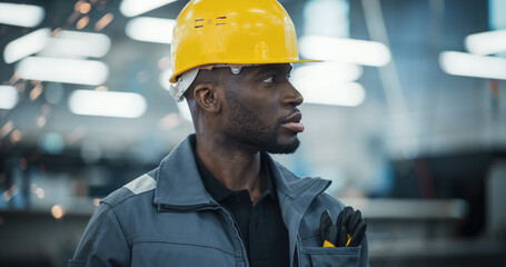 Smart Male Engineer in a Yellow Hard Hat Working in a Modern Metal Component Production Factory....