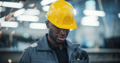 Smart Male Engineer in a Yellow Hard Hat Working in a Modern Metal Component Production Factory....