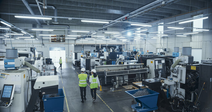 Establishing Footage with Professional Multicultural Colleagues Working at an Industrial Production Plant. Team Producing Metal Components with Heavy Duty Tools and CNC Milling Equipment