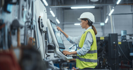 Female Machinery Technician Using Laptop Computer and Programming a CNC Machine at an Advanced...