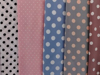 brightly colored polka dot fabrics are showcased in fabric store. each fabric features distinct...