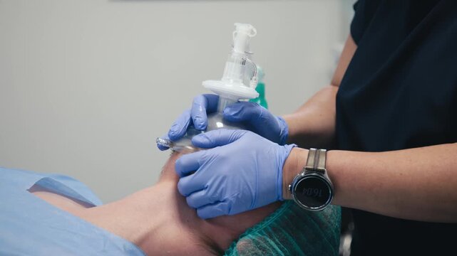 An anesthesiologist holding an anesthesia mask on a patient&rsquo;s face. Concept patient care and safe anesthesia administration.