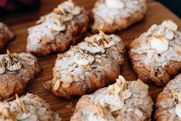 Freshly baked croissants with almond flakes in bakery display window.