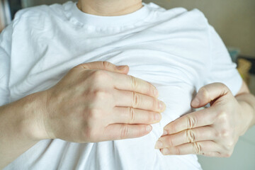 Close up of person in white shirt adjusting fabric with hands.