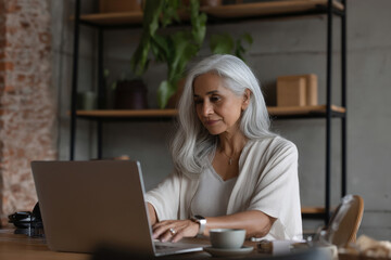 A mature Hispanic woman designs a comprehensive employee feedback survey on her computer, fine-tuning questions to ensure inclusivity,