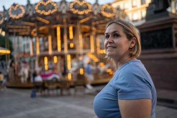 Beautiful smiling woman enjoying life with positive attitude, carousel blurred in background,...