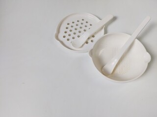 White Set of children's bowls, grater and spoons on the white background. Baby tableware. Nutrition and first level Baby's feeding concept