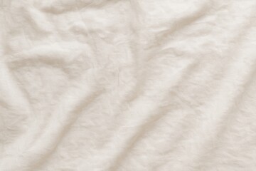 Naklejka premium Soft beige fabric texture with natural folds and wrinkles used in clothing, textile, and decor imagery