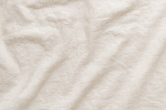 Soft beige fabric texture with natural folds and wrinkles used in clothing, textile, and decor imagery