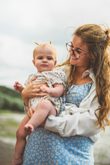 mother and baby child girl at the sunset on the waterscape view from back