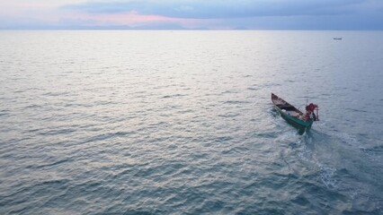 Naklejka premium Koh Tonsay, a stunning paradise in Cambodia, offers breathtaking aerial views showcasing a tranquil boat navigating calm waters as the sun rises, inviting relaxation.