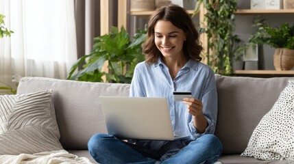 The woman enjoying online shopping with a laptop and credit card in her living room.