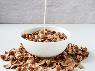 Chocolate corn flakes Cereal with pouring milk on white background