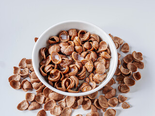 Chocolate corn flakes with milk in a bowl on white background