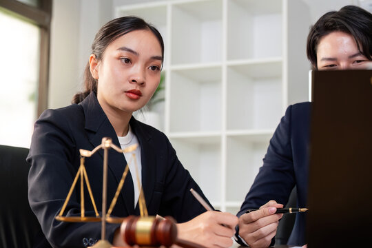 Fototapeta Legal Consultation. Young female lawyer discussing case details with client in office.