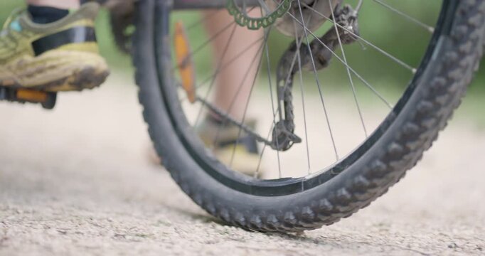 Abstract mountainbiker getting ready to ride. Man riding a mountainbike on a dusty dirth road path. Closeup pedal shoe and gear shift. Recorded at 120 fps on cinema camera.
