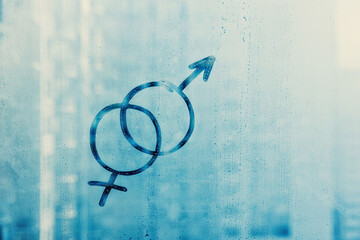 two doodle symbols of male and female on foggy blue glass window