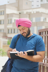 Vertical Photo of Happy Sikh Indian Student Writing in Notebook