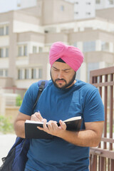 Vertical Photo of Sikh Indian Man Writing in Notebook