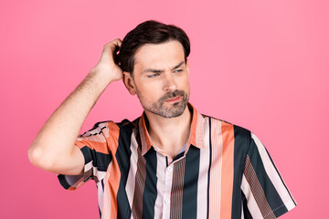 Casually dressed young man scratching his head with a puzzled expression, featuring stylish striped...