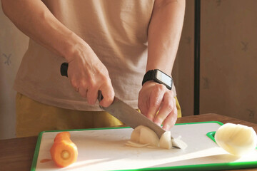 Chopping onion on cutting board in home kitchen