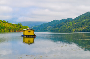 Fototapeta premium Tranquil Lakeside Cabin with Mountain Backdrop