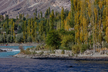 Autumn view Flowing blue water of Gilgit River with Hindu Kush mountain range in the background,Gahkuch, Pakistan.