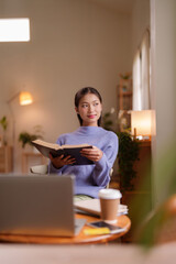 Asian adult woman enjoys tranquil moment reading book at home cozy setting peaceful learning personal development