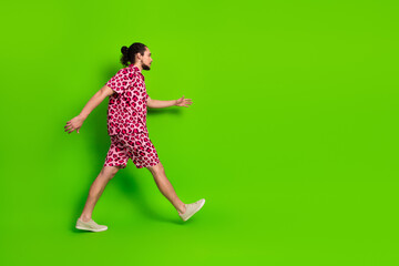 Young man wearing stylish leopard print outfit walking confidently against vibrant green background...
