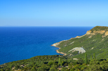 A beautiful blue ocean with a mountain in the background. The sky is clear and the sun is shining