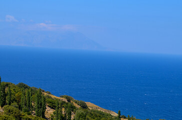A beautiful blue ocean with a mountain in the background. The sky is clear and the sun is shining