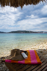 Sunscreen, Hat, and Towel on a Lounger at a Pebble Beach