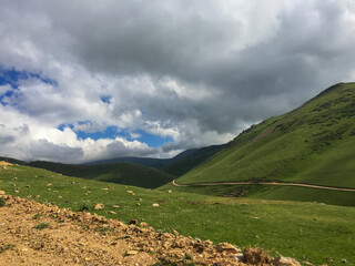 Mountain Road under Dramatic Sky in a Remote Green Valley