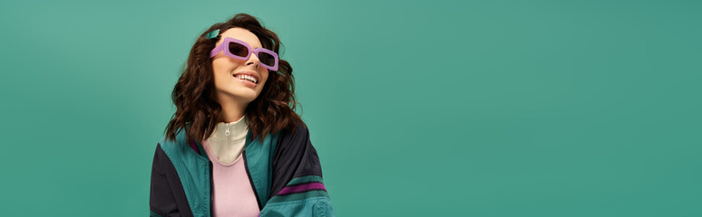 Stylish young woman exudes confidence in trendy sporty outfit against turquoise backdrop